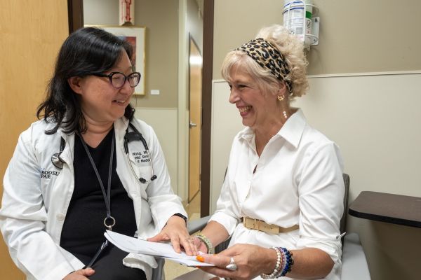 A doctor speaks with a female patient in an exam room