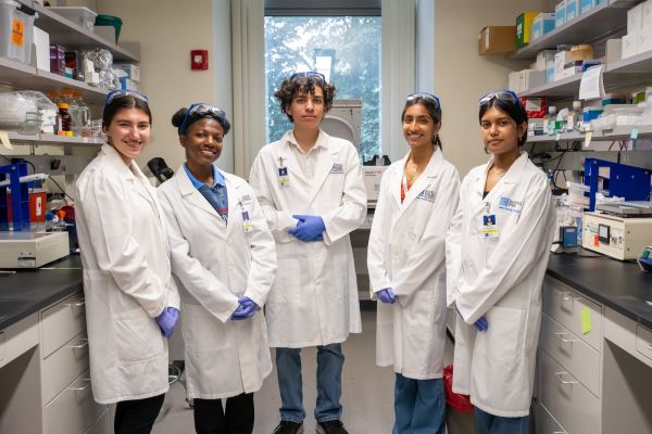 A group of 5 interns who are part of the High School SURE-CAN Program pose in a lab together