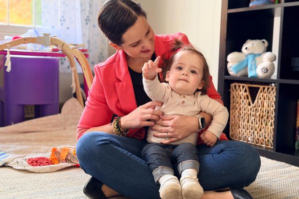 A mother sits in a playroom holding her child