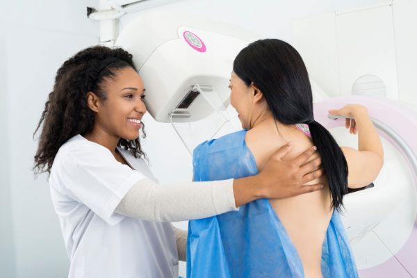A female doctor assists a patient before they receive a mammogram