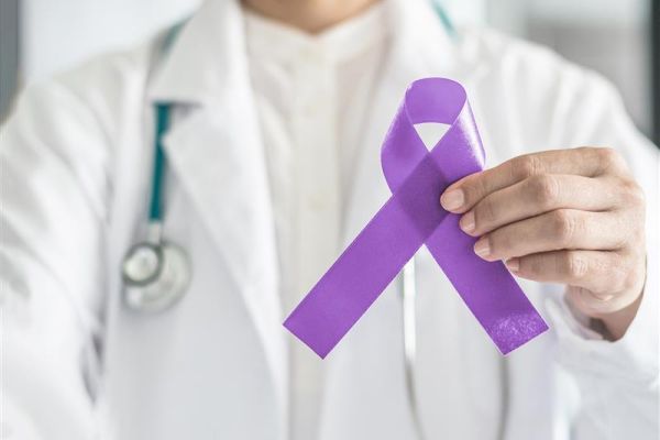 Doctor holding a purple testicular cancer ribbon