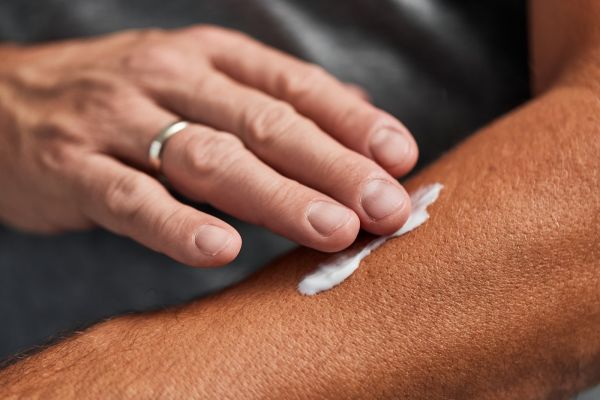 A man rubs lotion into his arm 