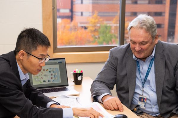 Two scientists discuss research in front of a computer