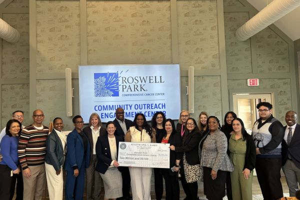 Group stands around government officials presenting a check