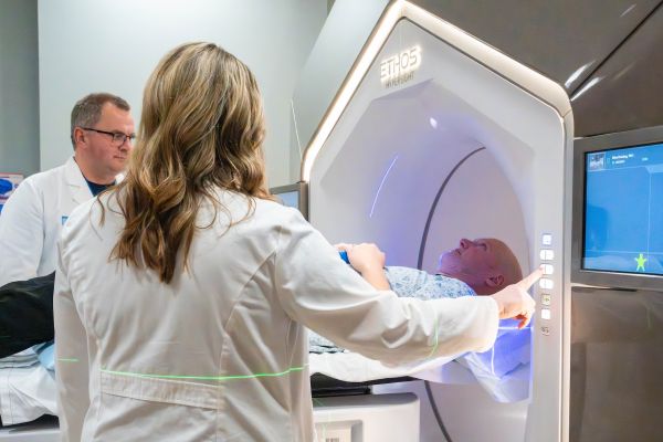Patient about to undergo radiation therapy with two doctors looking on.