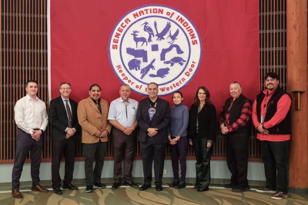 Group stands in front of Seneca Nation flag