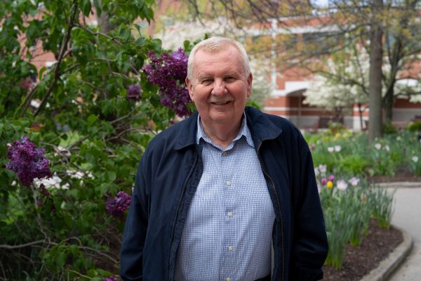 A man stands in a park near some flowers