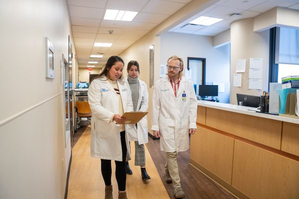 Dr. Nicole Gaulin, head of the Gynecologic Oncology Fellowship, walks and talks with two GYN fellows in the halls of the hospital.