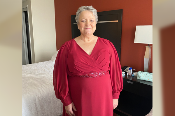 Cindy Mantai, breast cancer Care Network patient, smiles in a red dress