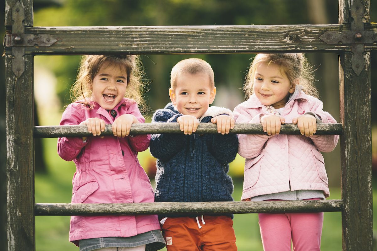 Three children standing at a wooden fence