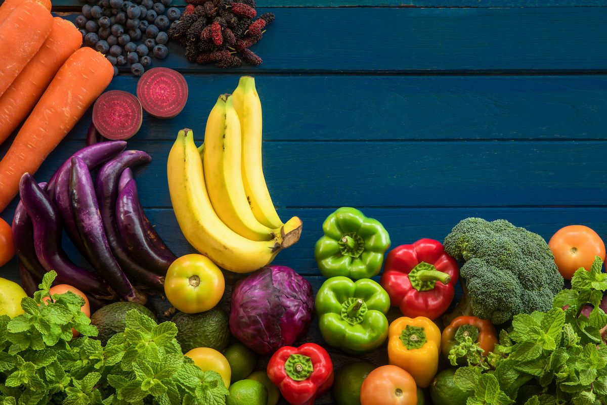 An arrangement of colorful fruits and vegetables on a dark-blue table