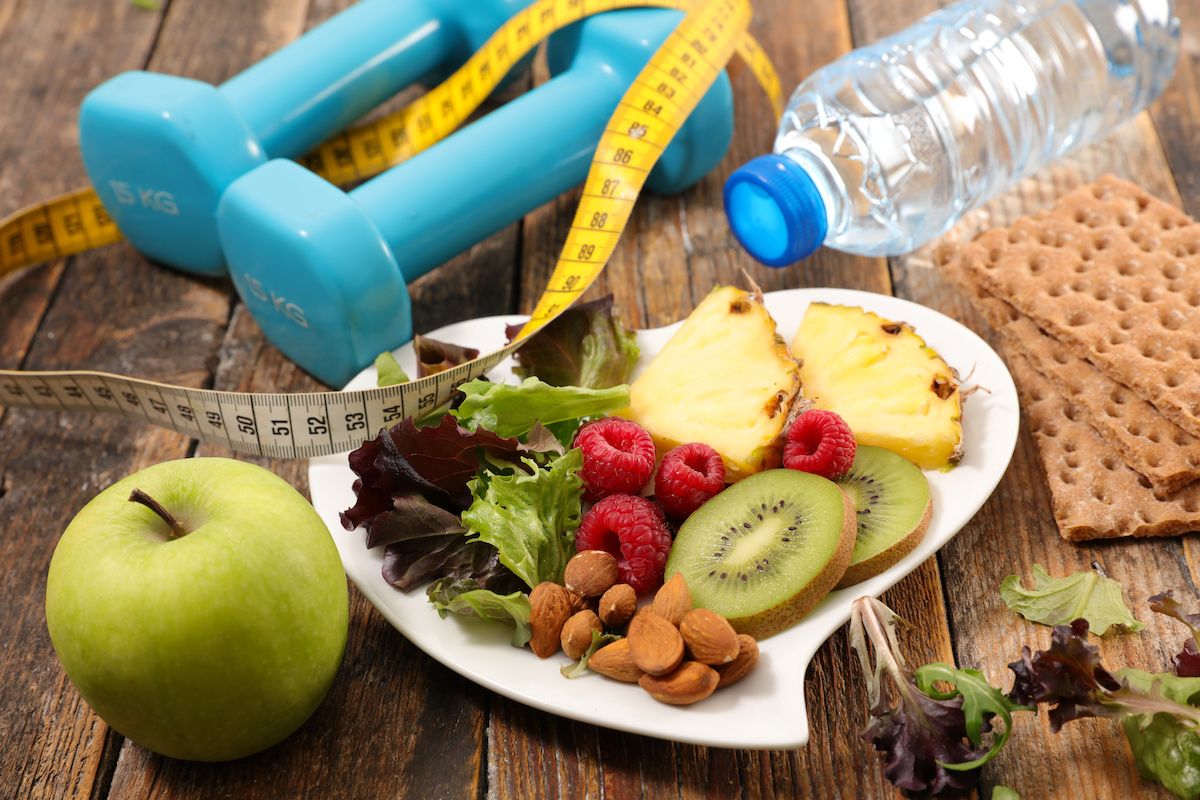 A table with hand weights, water bottle and healthy food