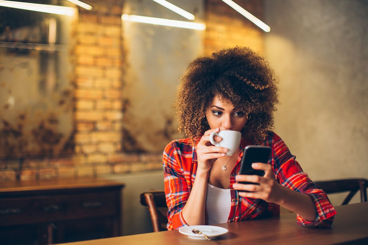 Woman at a coffee shop looking at her smartphone