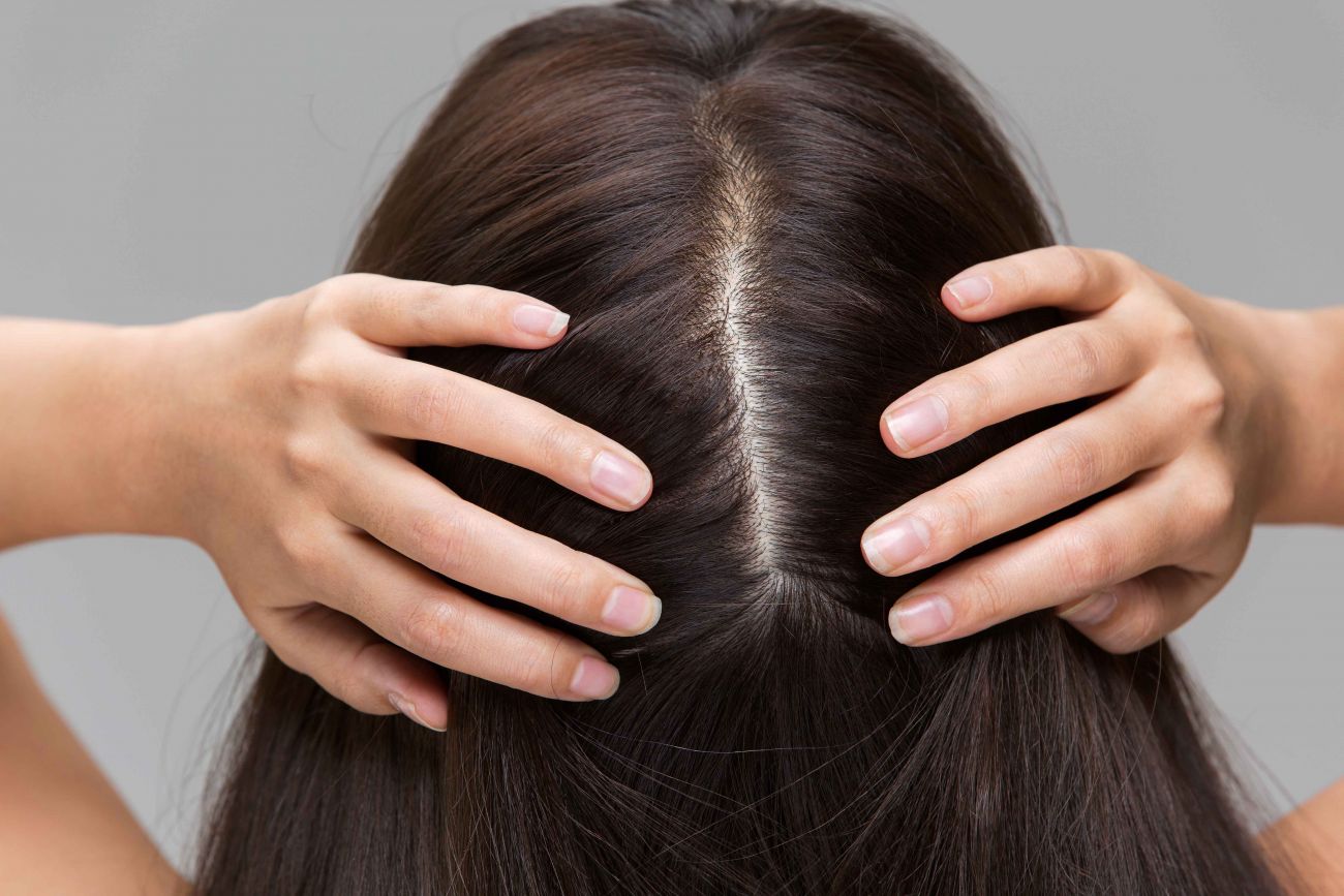 Young woman checking the back of head for skin cancer