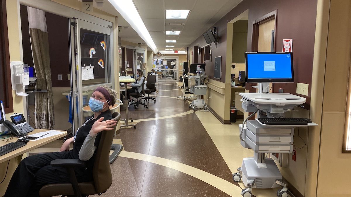 A nurse waves hello from a work station in an inpatient unit 