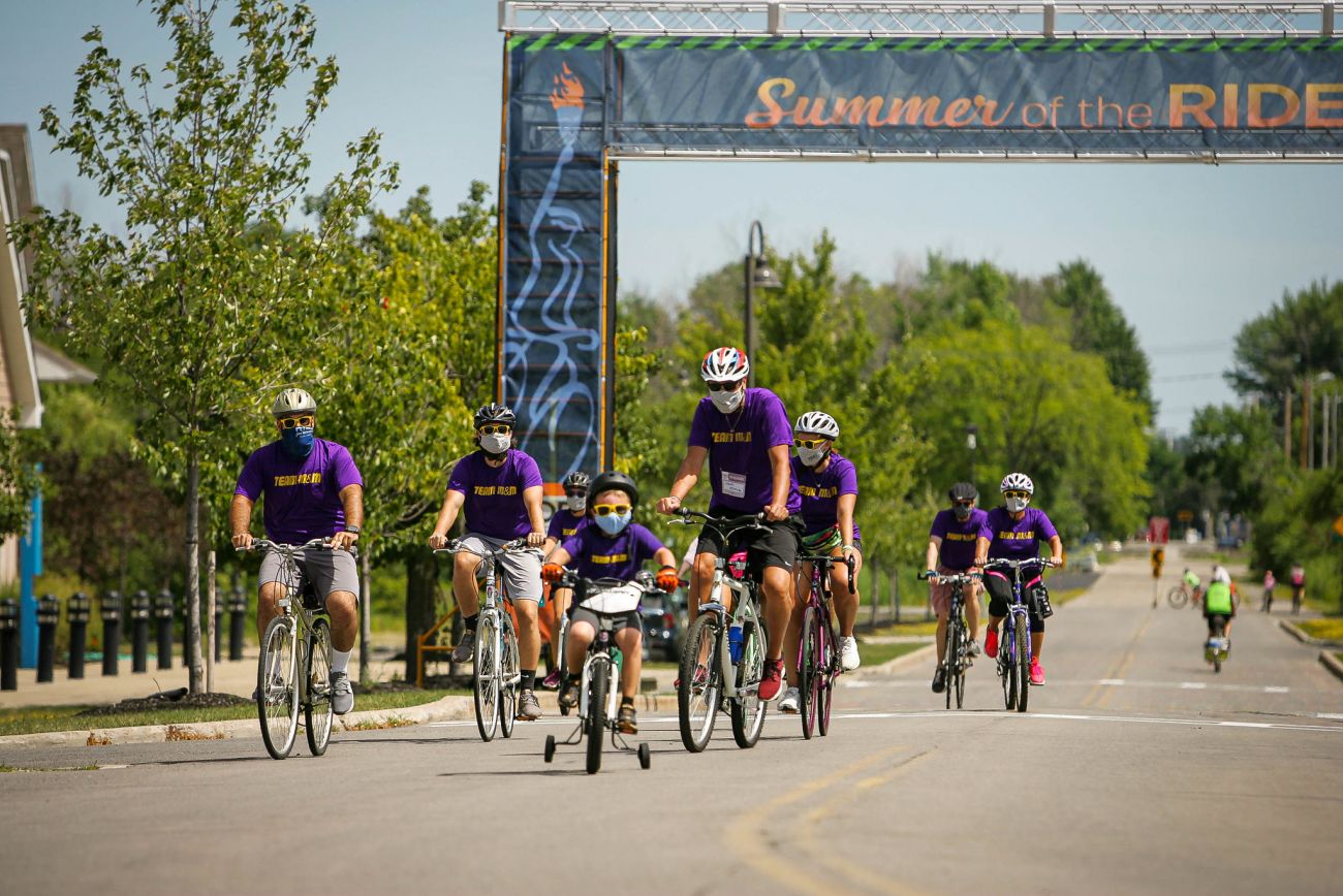multiple adults and one child in purple T-shirts riding bikes for the Ride for Roswell