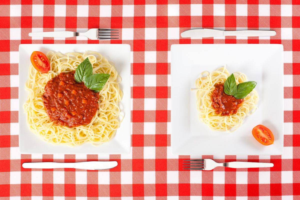 A regular portion of spaghetti next to a very large portion