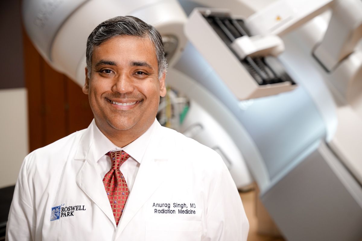 Dr. Singh standing in front of a radiation machine.