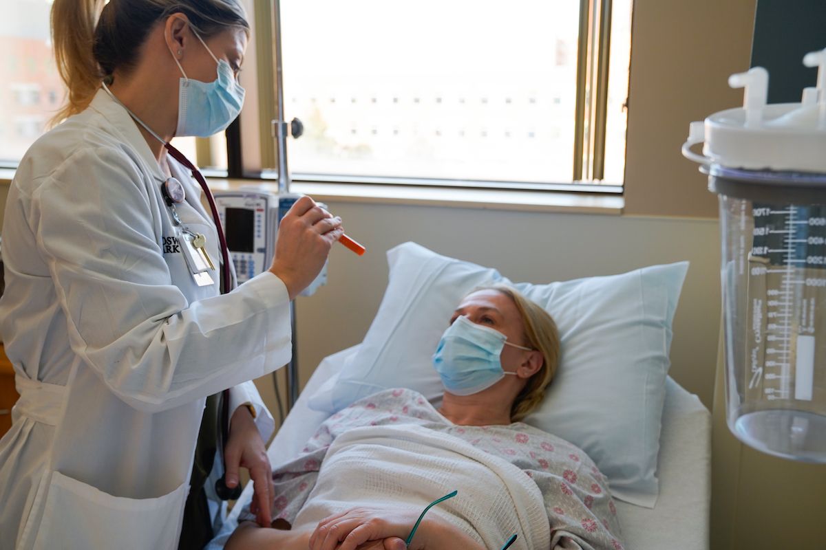 A doctor uses a penlight to examine a patient's eyes.