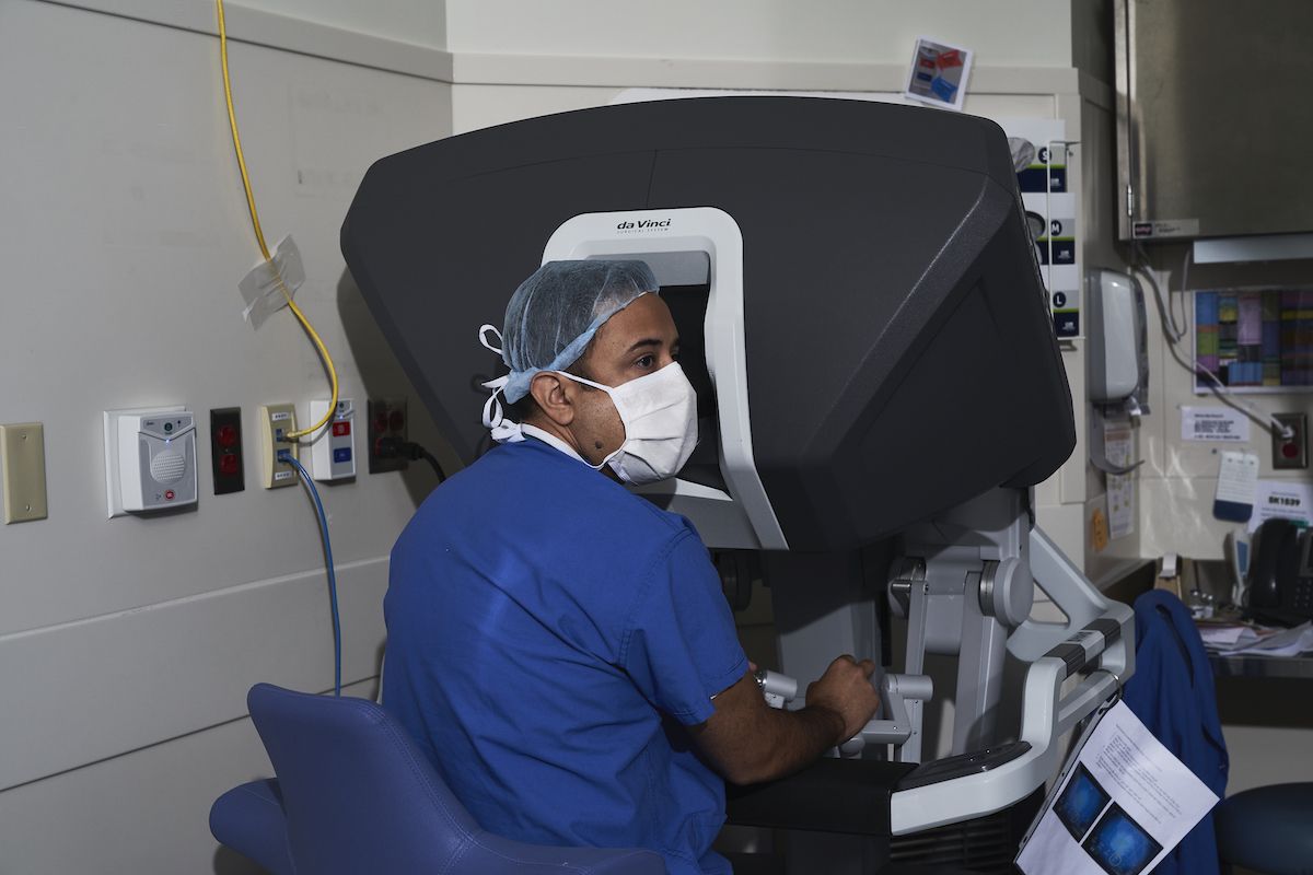 Doctor performs surgery while seated at the console of a robotic surgical system.