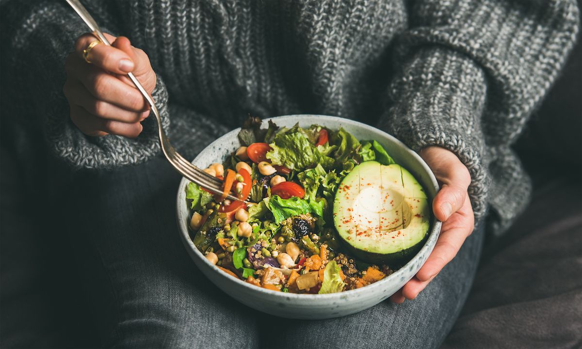 Person in a grey sweater eating vegetarian poke bowl