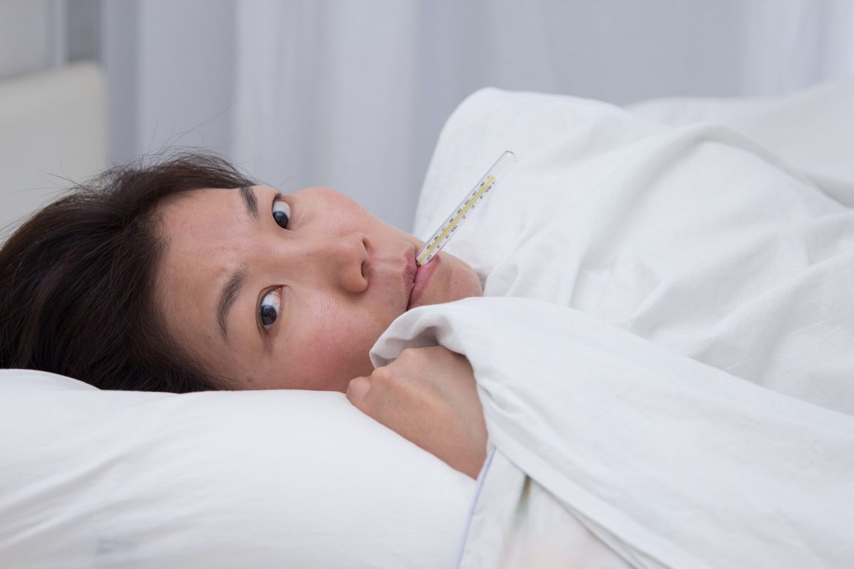 Woman in bed with a thermometer in her mouth