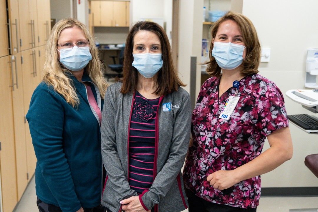 Three women wearing cloth face masks stand shoulder to shoulder at the entrance to the Donor Center at Roswell Park. 