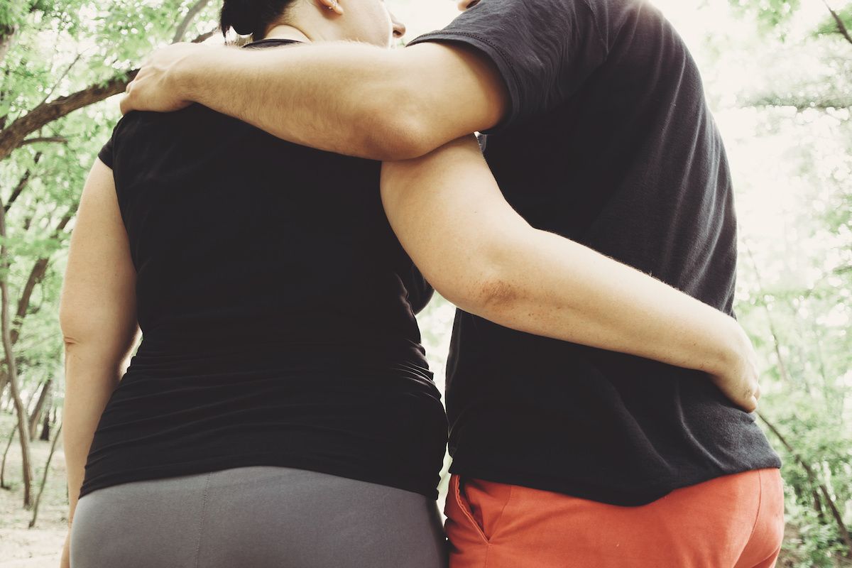 An obese couple with their arms around each other