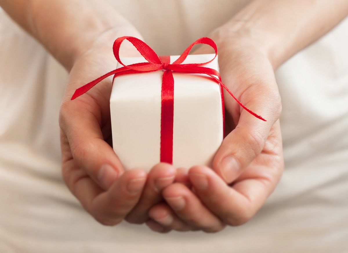 Hands holding a small present wrapped with a red bow