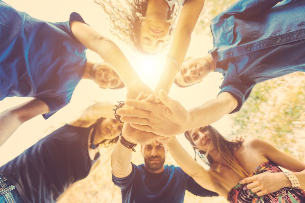 Group of young adults putting their hands together