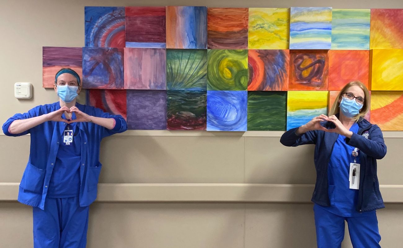 Two nurses in masks show heart hands