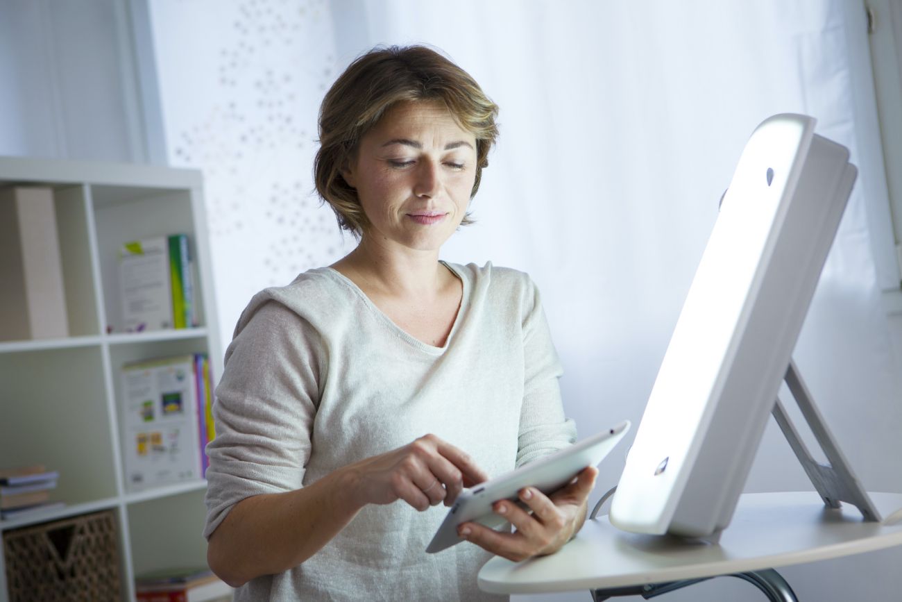 Woman sits in front of sun lamp to aid season defective disease