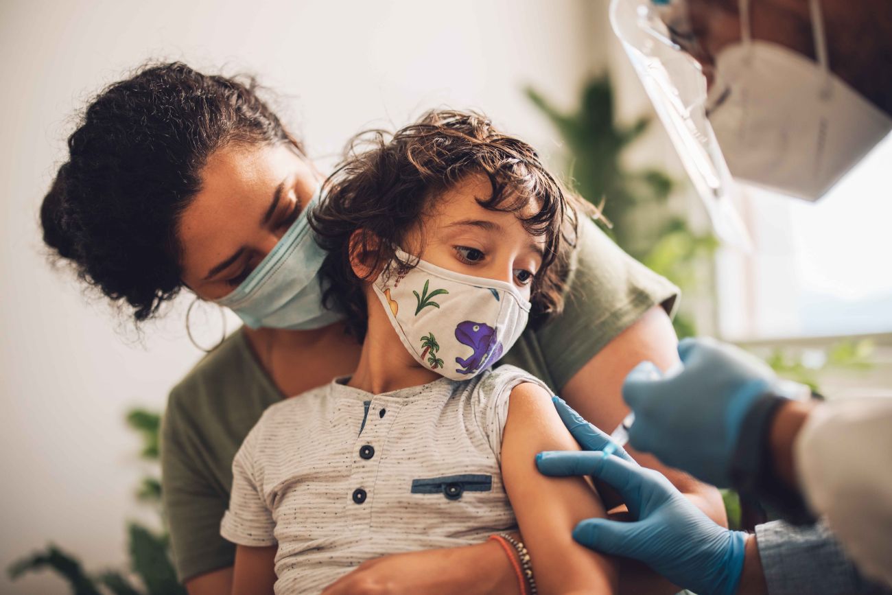 Mother holding child while receiving a vaccine shot 