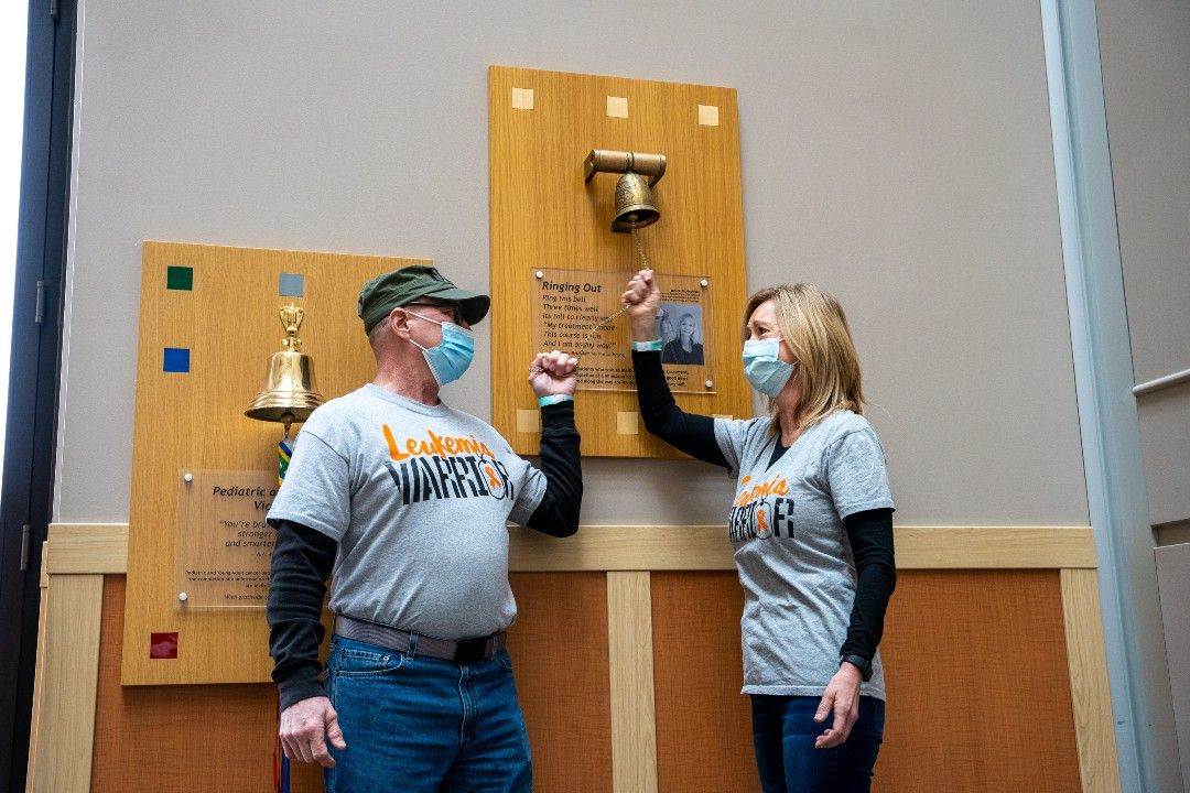 Kevin and Marilyn Sittniewski, wearing gray shirts that read "Leukemia Warrior," ring the Victory Bell together after they both beat cancer. 