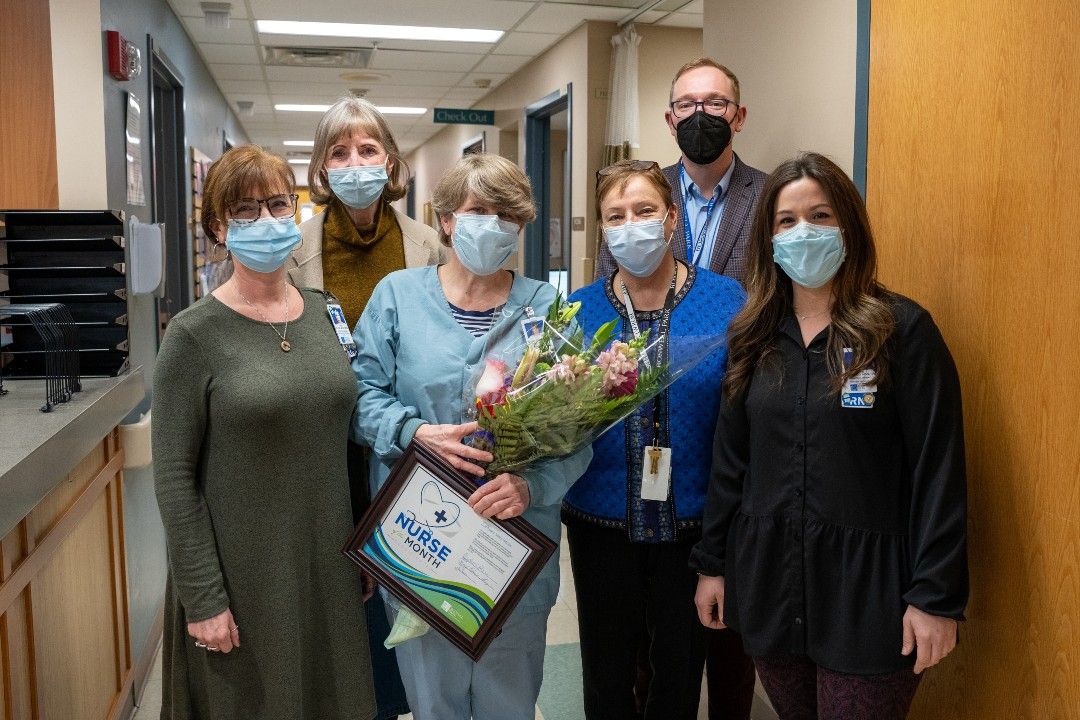 Mary Colleen House, middle, holds flowers and a framed certificate as Roswell Park's Nurse of the Month for February 2022. 