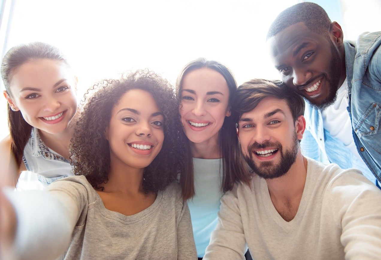 A group of young people, including three women and two men, smile at the camera.