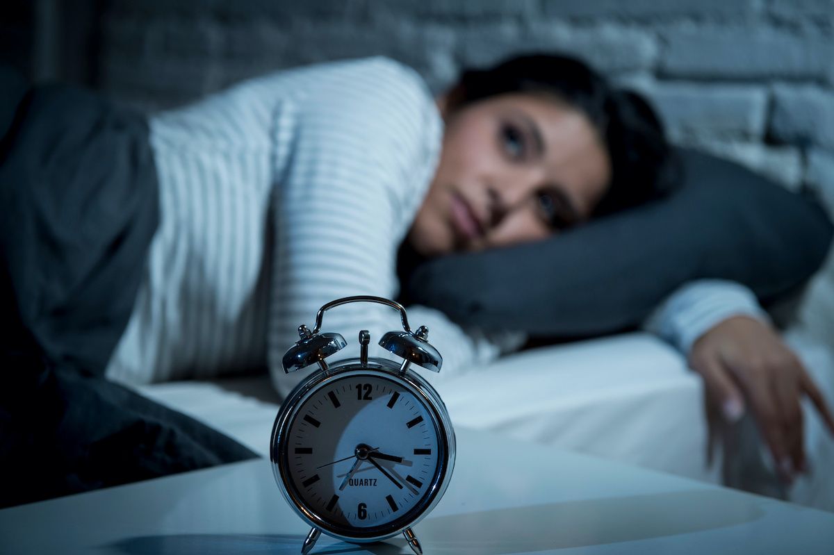 Woman awake in bed watching alarm clock