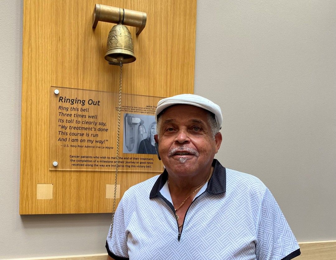 Rochester Davis, a prostate cancer survivor, stands next to the Victory Bell in the lobby of Roswell Park Comprehensive Cancer Center. 