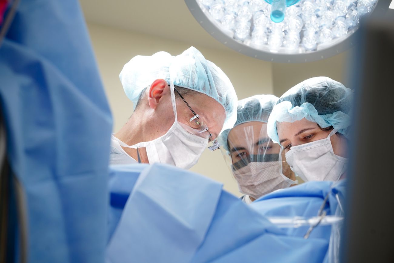 Dr. John Kane in surgery with two assistants looking on.