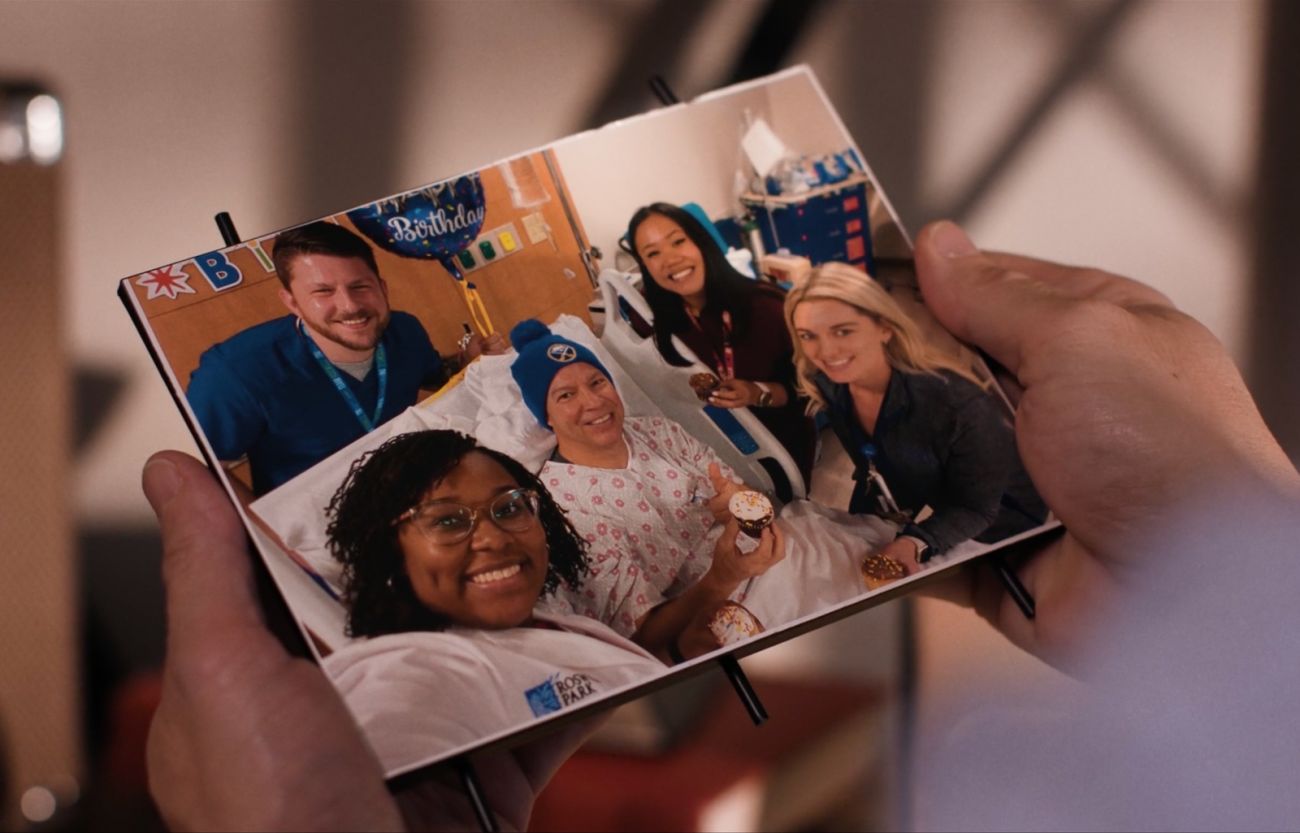 a person holds up a framed photograph of a patient in a hospital bed