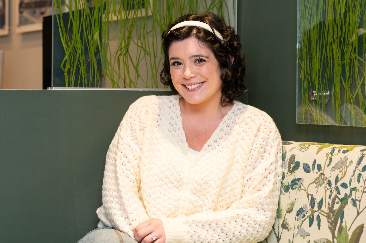 Young woman sitting on bench with hands crossed on her lap