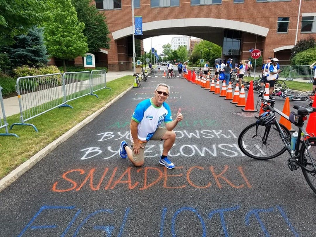 A man crouches down by his last name, written in chalk, outside Roswell Park Comprehensive Cancer Center, during the week leading up to the Ride for Roswell. 