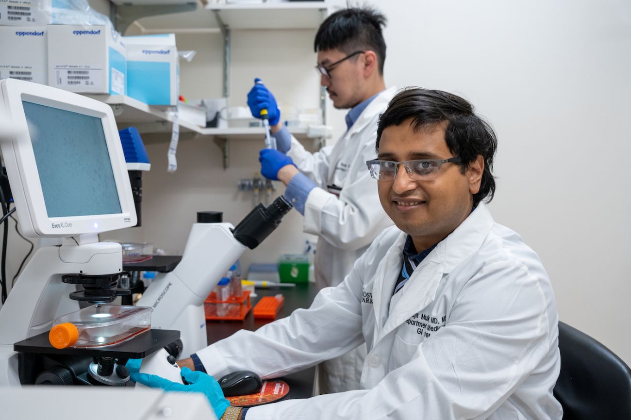 Dr. Sarbajit Mukherjee poses with a microscope in his lab 