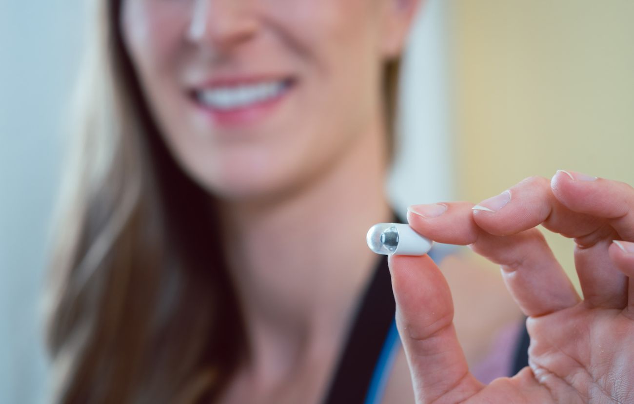 Woman holding a small camera capsule used to perform a capsule endscopy