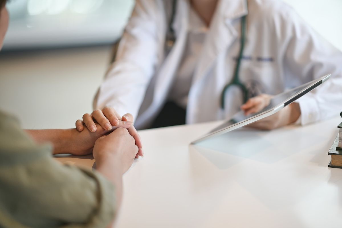 Doctor holding young woman's hand across a table