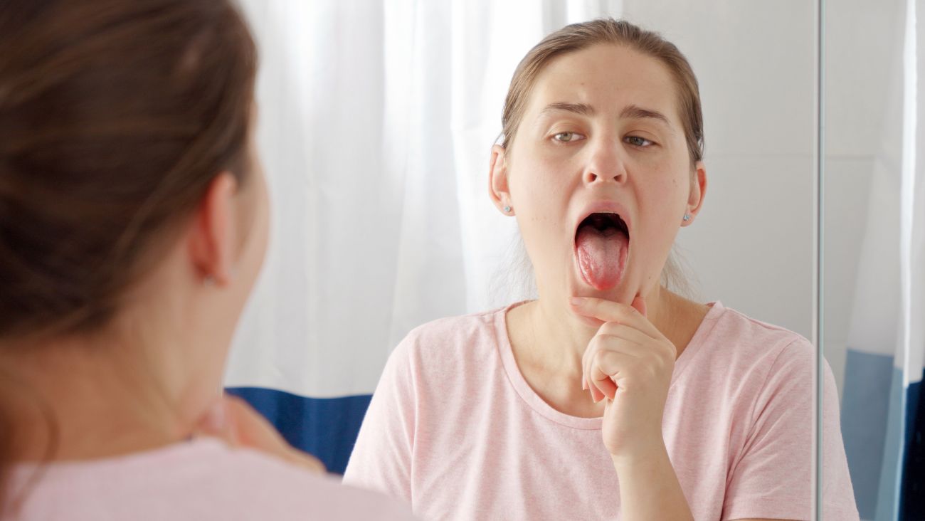 Woman looking at her tongue in the mirror