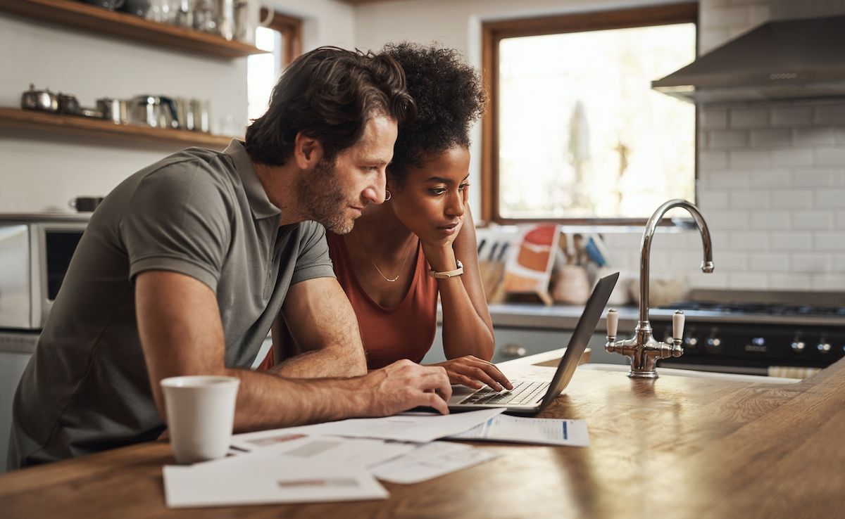 Young couple looking at a laptop in their kitchen going over finances