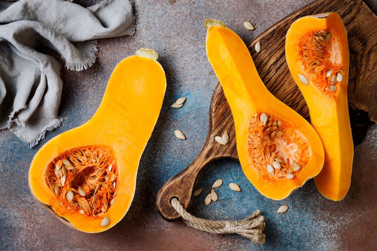 3 slices of butternut squash and seeds displayed on a cutting board