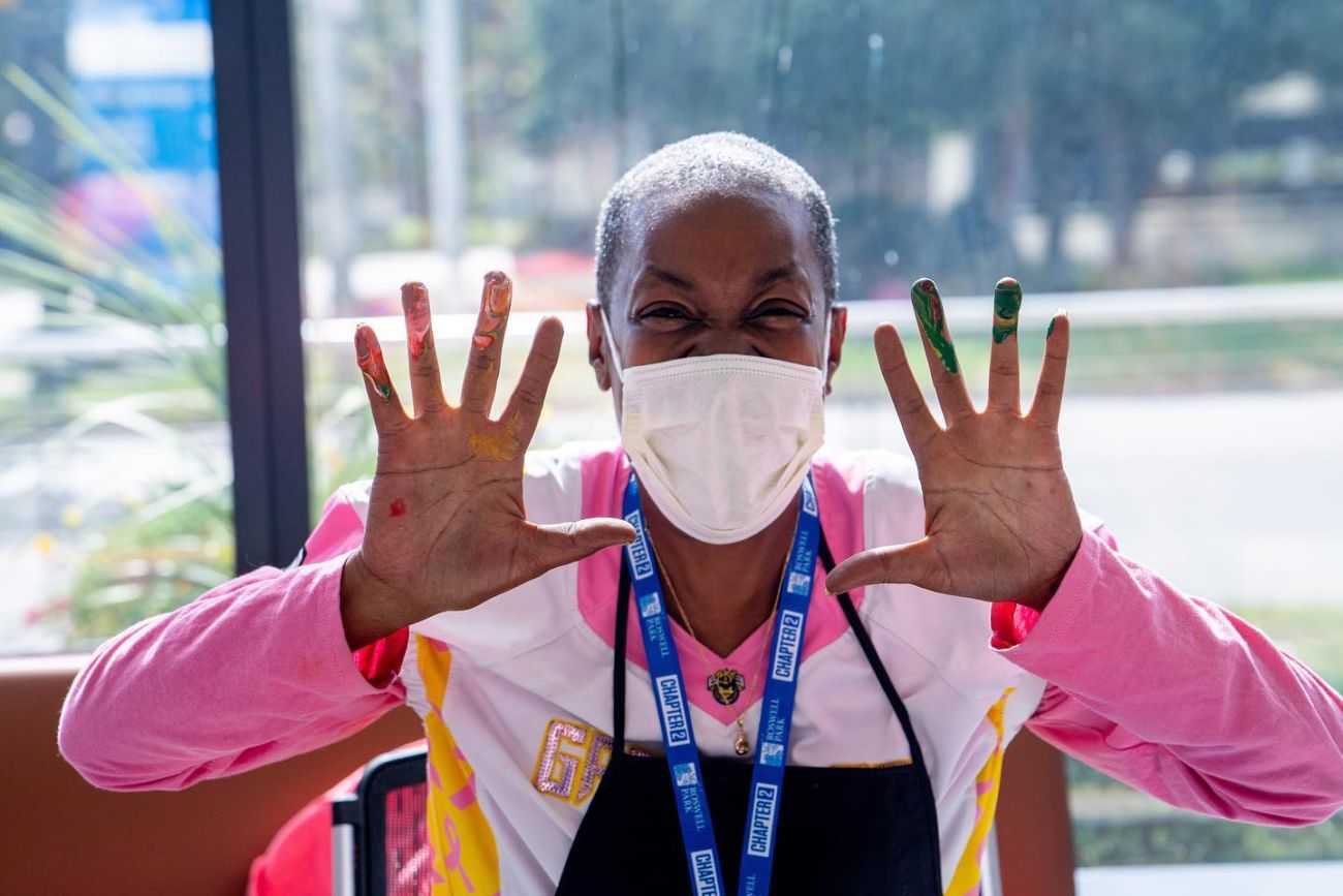 Chapter 2 attendee poses with paint on their hands during the painting session for survivors.