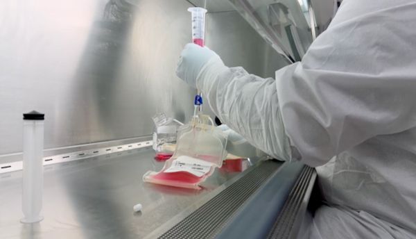 Tight shot of person's arm holding a tube of red liquid in a medical lab